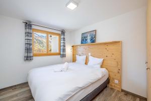 Schlafzimmer mit einem großen weißen Bett mit einem Kopfteil aus Holz in der Unterkunft Chalet Amerhone - Luxury chalet With Jacuzzi in Riddes