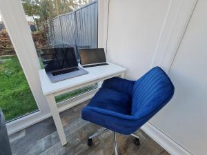 a desk with a laptop and a blue chair at Elm Park Cheerful 4-Bedroom Holiday Home in Hornchurch