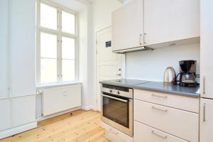 a kitchen with white cabinets and a stove top oven at Scandinavian Style 3BR in Copenhagen City Centre in Copenhagen