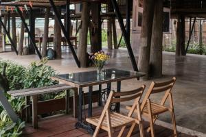 a glass table with two chairs and a vase of flowers at Art House at Chiangdao - Lake House in Chiang Dao