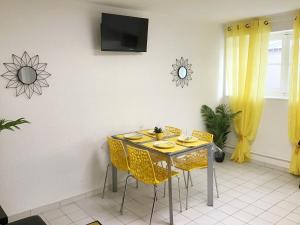 une salle à manger avec une table et des chaises jaunes dans l'établissement Appartements Sun, parking, centre ville , proche Sanctuaires, à Lourdes