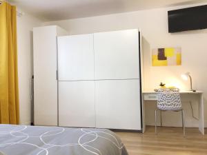 une grande armoire blanche dans une chambre avec un bureau dans l'établissement Appartements Sun, parking, centre ville , proche Sanctuaires, à Lourdes