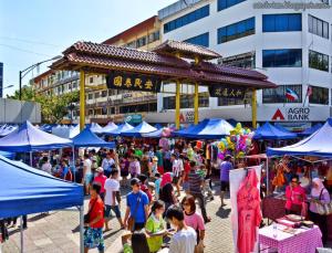 una multitud de personas caminando por un mercado con sombrillas azules en Jesselton Quay homestay with Free 1 parking by StayPlace en Kota Kinabalu
