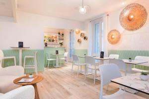 un restaurant avec des tables et des chaises blanches et un comptoir dans l'établissement Hotel Florence Nice, à Nice