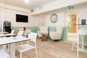 a waiting room with white chairs and tables at Hotel Florence Nice in Nice