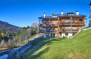una gran casa de madera en una colina con un patio verde en The Wooden House Cortina, en Cortina dʼAmpezzo