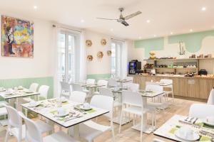 a dining room with white tables and white chairs at Hotel Florence Nice in Nice