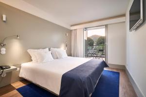 a hotel room with a large bed and a balcony at Ribeira Collection Hotel by Piamonte Hotels in Arcos de Valdevez