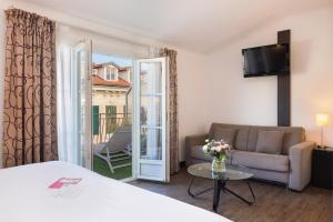 a room with a bed and a couch and a window at Hotel Florence Nice in Nice