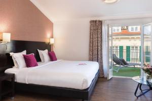 a hotel room with a large bed and a balcony at Hotel Florence Nice in Nice