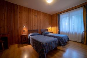 two beds in a room with wooden walls and wooden floors at Family Apartments Le Chalet in Champoluc