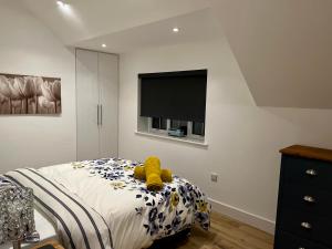 a bedroom with a bed with a teddy bear on it at Apple Tree Apartment in Hensol