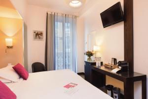 a hotel room with a bed and a desk and a window at Hotel Florence Nice in Nice