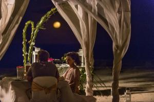 a man and woman sitting under a tent on the beach at night at Diamonds Mapenzi Beach - All Inclusive in Kiwengwa