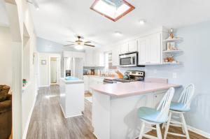una cocina con armarios blancos y taburetes azules en Tybee Southern Comfort, en Tybee Island
