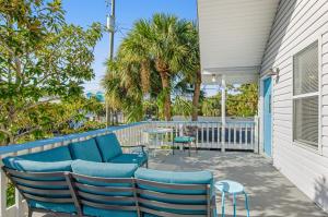 a patio with blue chairs and a table and palm trees at Tybee Southern Comfort in Tybee Island