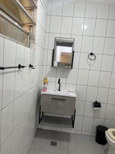 een wit betegelde badkamer met een wastafel en een spiegel bij Apartamento 2 Guarujá enseada 2 dorm, 200m praia Ed Carpentier in Guarujá