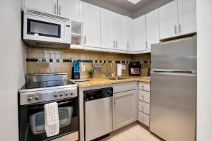 una cocina con electrodomésticos de acero inoxidable y armarios blancos en National at 888 Sixth Avenue - Furnished Apartments, en Nueva York