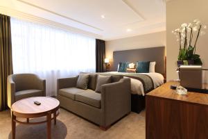 a hotel room with a bed and a couch and a table at Thistle London Marble Arch in London