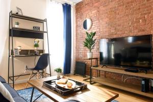 a living room with a large television and a brick wall at 428-4R prime midtown large 2 BR Newly Furnished in New York