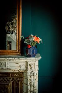 un miroir et un vase avec des fleurs sur une table dans l'établissement Relais M B&B, à Frasnes-lez-Anvaing