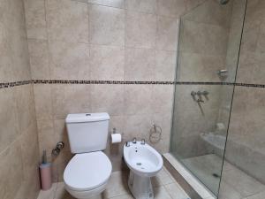 a bathroom with a toilet and a glass shower at Luminoso departamento en zona residencial in Mendoza