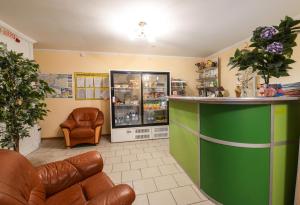una sala de espera con un mostrador verde y sillas de cuero en Viktoria Hotel, en Cherepovets