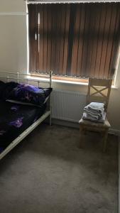 a bedroom with a bed and a chair and a window at Spacious Double Room in Leicester