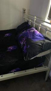 a bed with a purple comforter and pillows on it at Spacious Double Room in Leicester