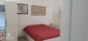 a small bedroom with a bed with a red blanket at Porta Merlonia house in Forlì