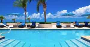 a swimming pool with chairs and umbrellas at New Listing La Vista Azul Spacious 1 Bedroom Condo in Turtle Cove