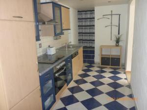 a kitchen with blue cabinets and a checkered floor at Ferienwohnung Christine in Heckendalheim