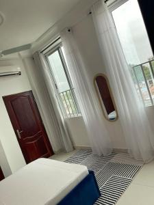 a bedroom with a bed and a door and windows at Superbe appartement cosy-chic in Cotonou
