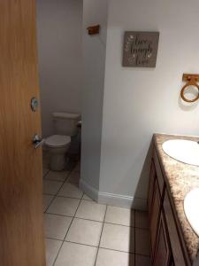 a bathroom with a toilet and two sinks and a door at North Getaway Cottage in Williamstown