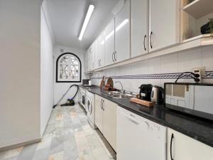 eine Küche mit weißen Schränken und einem Waschbecken in der Unterkunft El Mirador de Mijas Piscina y Parking gratis in Málaga