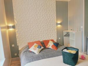 Un dormitorio con una cama con almohadas. en VITTEL LOC'S - LE 216, classé 3 étoiles proche des Thermes et tous commerces, en Vittel