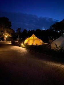 Tienda iluminada al lado de una carretera por la noche en Stargazer Tent met sterrenuitzicht, en Callantsoog