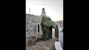 una antigua casa de piedra con mesa y sillas en Room in Studio - Artemis Studio Pyrgi en Platis Yialos Mykonos