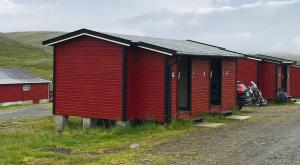 una fila de edificios rojos con una motocicleta aparcada delante en Hytte Camp Nordkapp - Red, en Skarsvåg