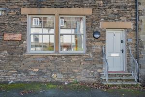 a brick building with a white door and a window at Esperance - Brand New, luxury studio with parking in Bowness-on-Windermere