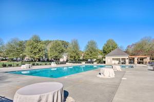 a swimming pool with white chairs and a building at Chic Gastonia Home with Deck, Fire Pit and Grill! in Gastonia