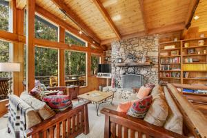 a living room with a stone fireplace and wooden ceilings at Tahquitz Rock Lodge in Idyllwild
