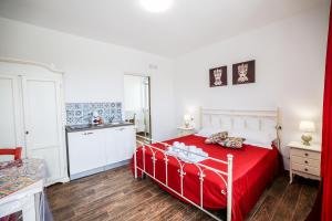 a bedroom with a red bed and a kitchen at Cà del Re Holiday in Partinico