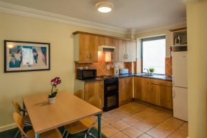 uma cozinha com armários de madeira e uma mesa e uma mesa e cadeiras em DCU Rooms Glasnevin - Campus Accommodation em Dublin