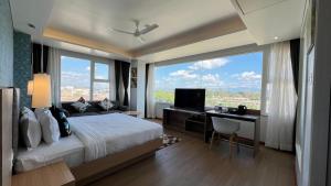 a bedroom with a bed and a desk and a large window at Aurora Boutique Hotel Imphal in Imphal
