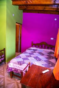 1 dormitorio con cama morada y mesa de madera en El Shaddai en Tilcara