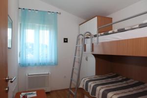 a small bedroom with a bunk bed and a ladder at Apartments Sea View Kozino in Kožino