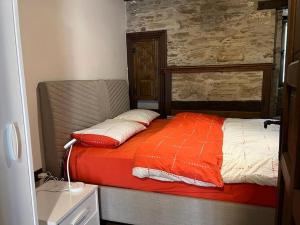 ein Bett mit einer orangefarbenen und weißen Bettdecke in einem Zimmer in der Unterkunft Holiday home in Şirince Centre in Selçuk