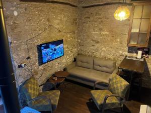 ein Wohnzimmer mit einem Sofa und einem TV an einer Steinmauer in der Unterkunft Holiday home in Şirince Centre in Selçuk