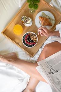 Eine Frau, die auf einem Bett mit einem Tablett Essen sitzt. in der Unterkunft SANA Capitol Hotel in Lissabon